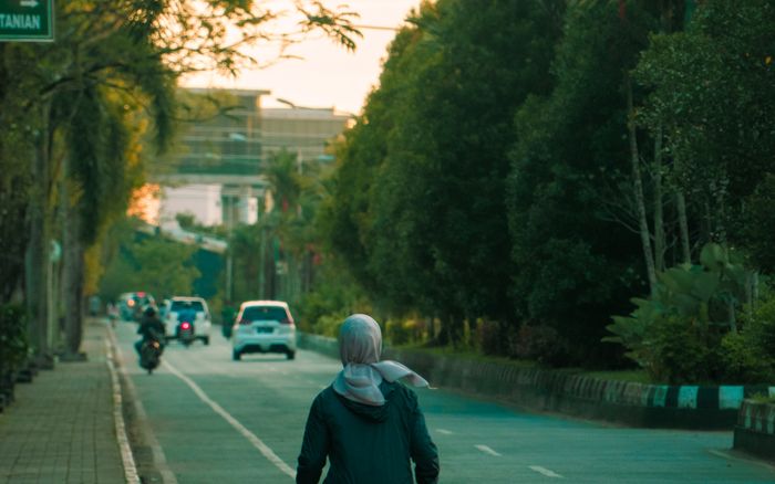 A person jogging down a quiet tree-lined street
