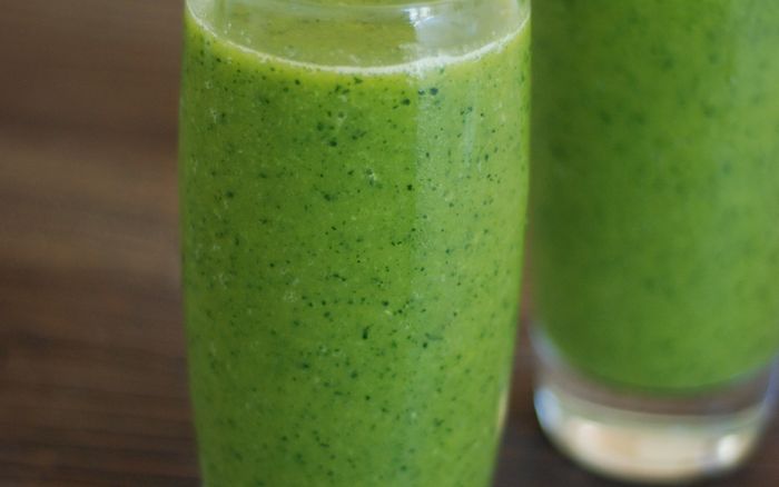 Two green smoothies in glasses on a rustic wooden table