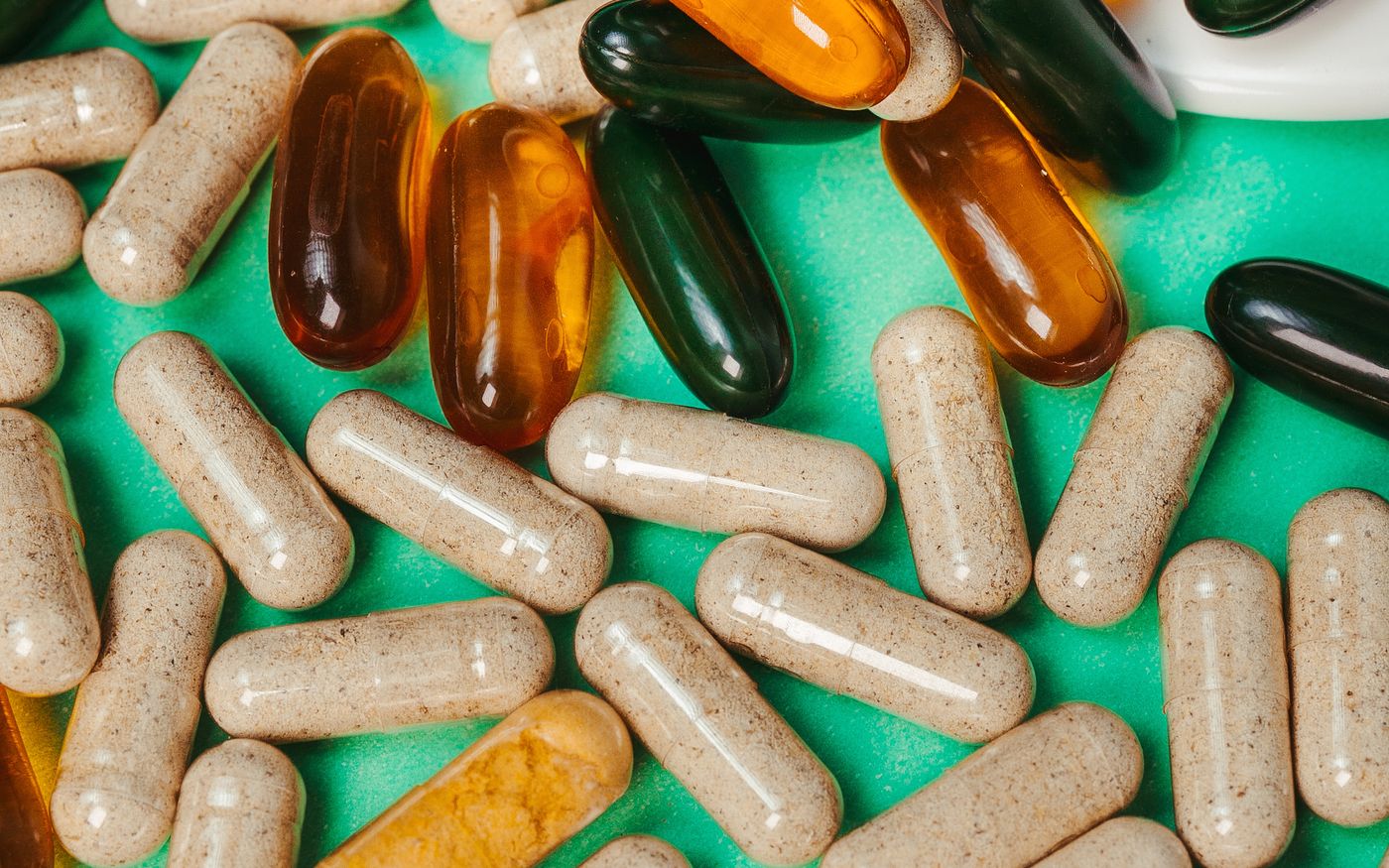 Close-up of assorted vitamins scattered on a green surface